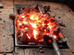 【1】コークスの炉で部材を加熱します。無垢な鉄が「赤み」を帯びていきます。